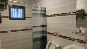 A bathroom with a striped shower curtain, a toilet, a sink, and a window with bars.