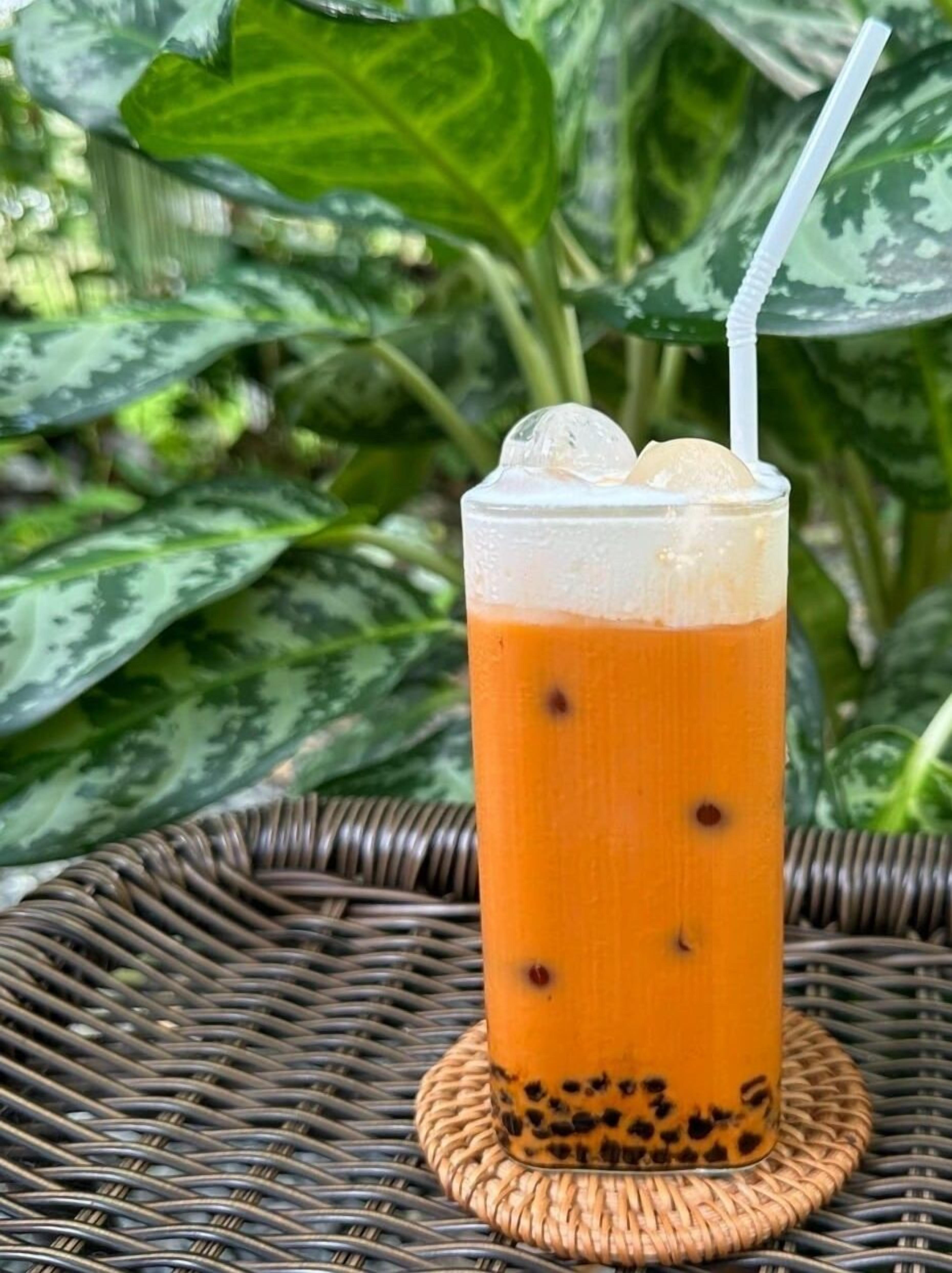 A glass of iced tea with tapioca pearls on a woven coaster.