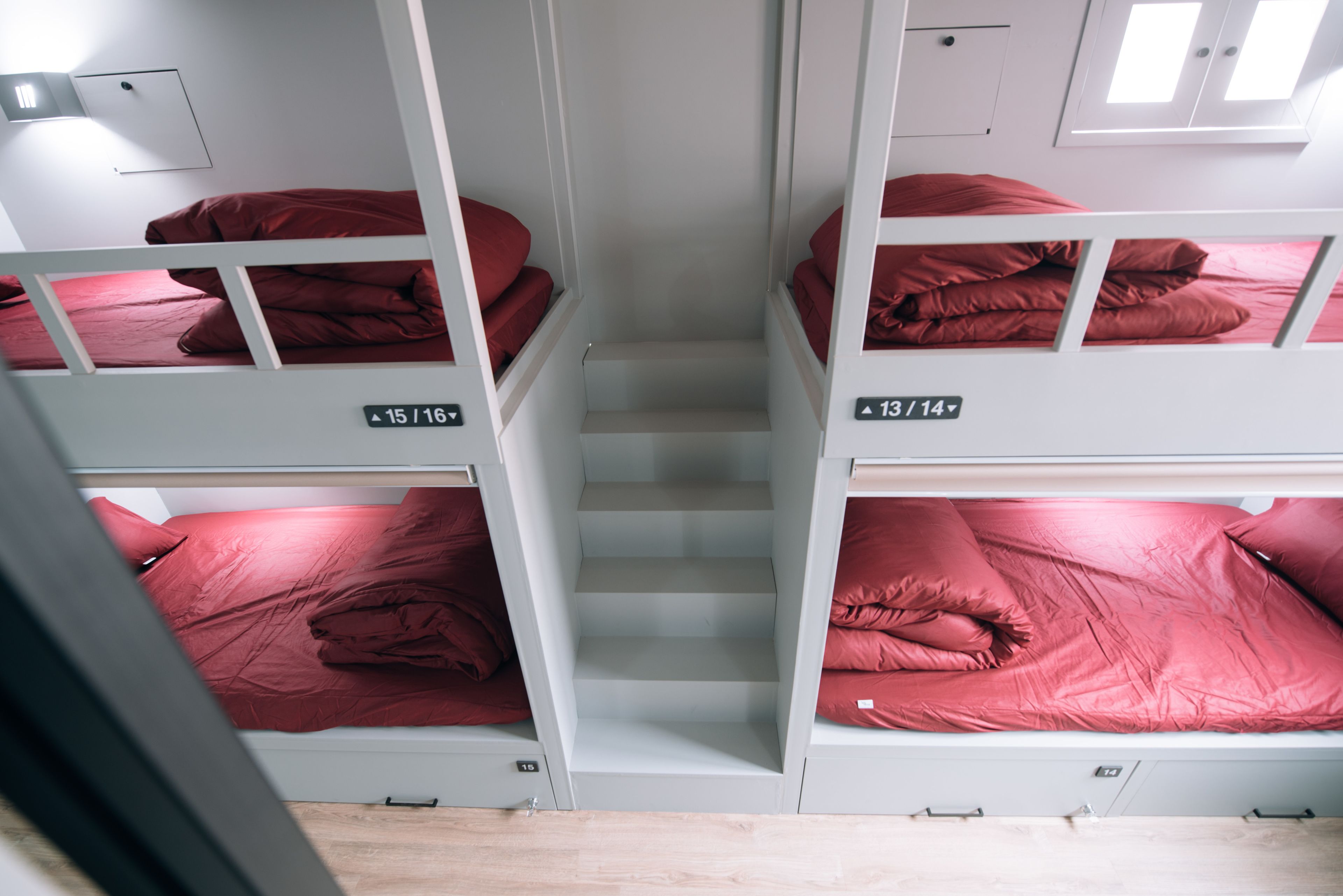 A dormitory-style room with bunk beds, each labeled with room numbers.