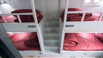 A dormitory-style room with bunk beds, each labeled with room numbers.