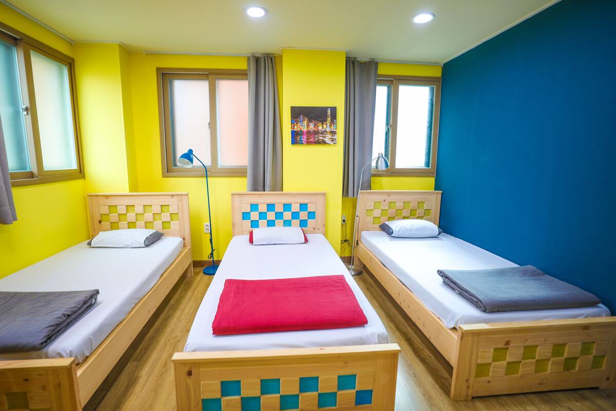 A room with three wooden beds, each with a checkered headboard, arranged in a row.