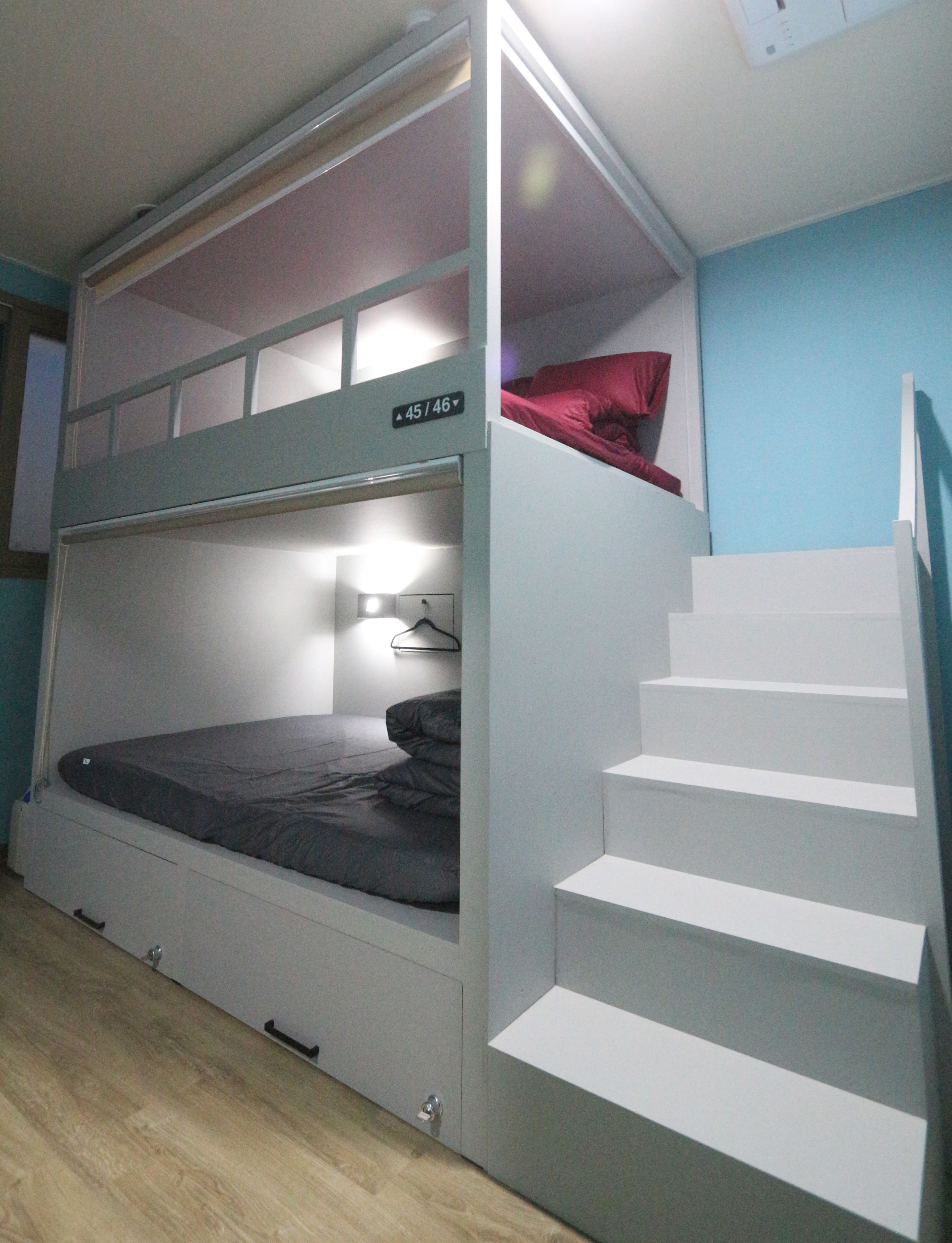 A bunk bed with a small desk and a staircase leading to an upper bunk.