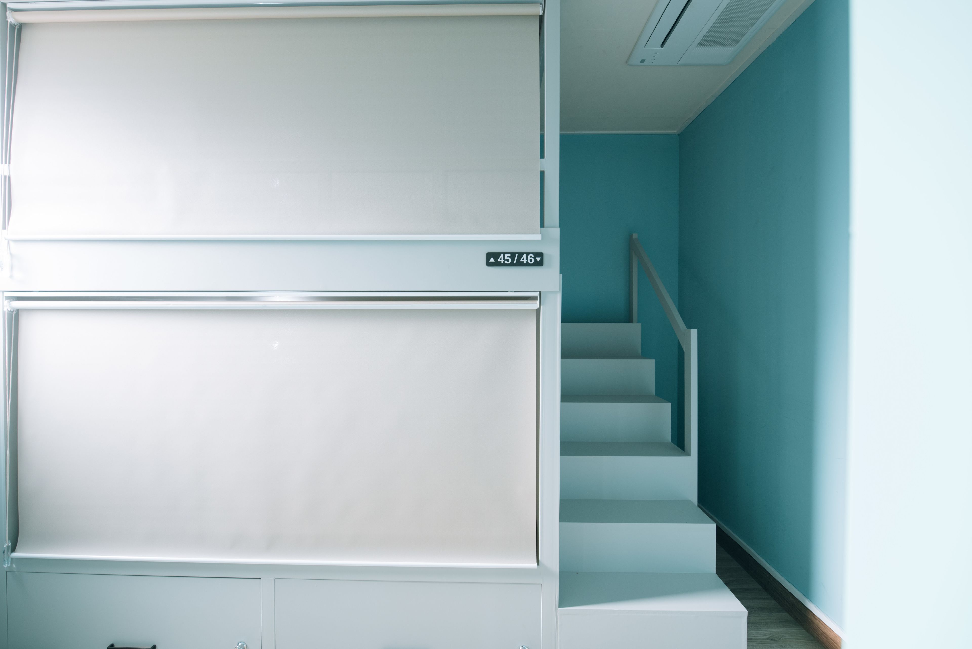 A staircase with a handrail, a sign indicating floor levels, and a light blue wall.