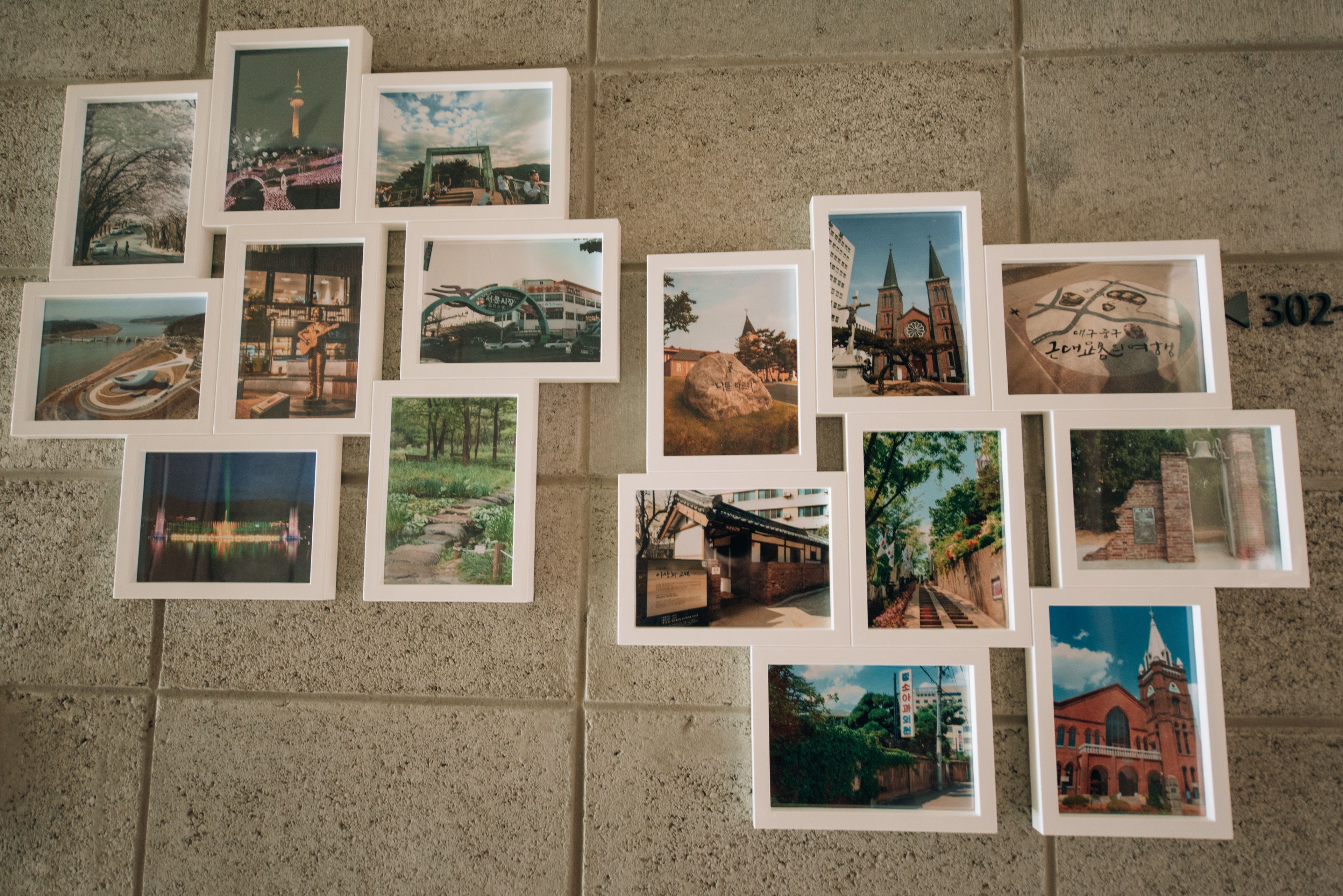 A wall with multiple framed photographs depicting various buildings and landscapes.
