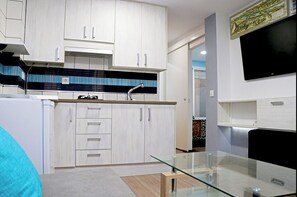A modern kitchen with white cabinets, a black backsplash, and a glass dining table. - Central 4 person apartment, Free Wi-Fi (CONIL DE LA FRONTERA)