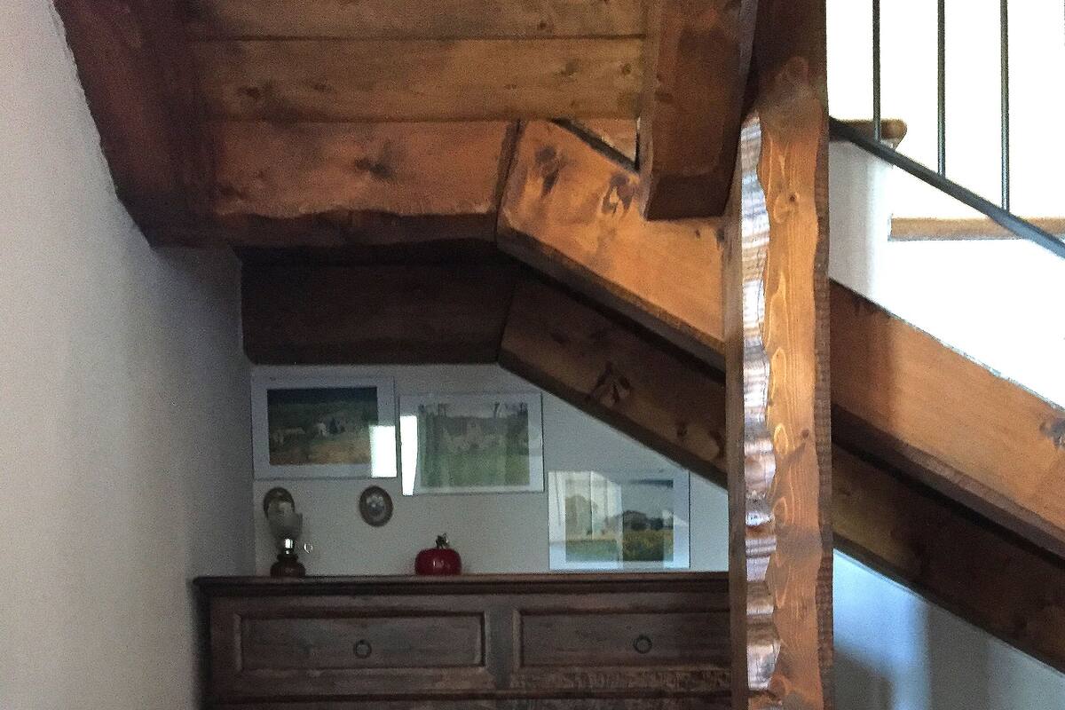 A rustic kitchen with wooden cabinets, a tiled floor, and a staircase leading to an upper level.