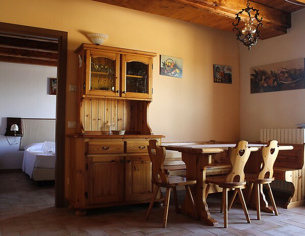 Una mesa de comedor de madera con sillas, un aparador con puertas de cristal y obras de arte en las paredes.