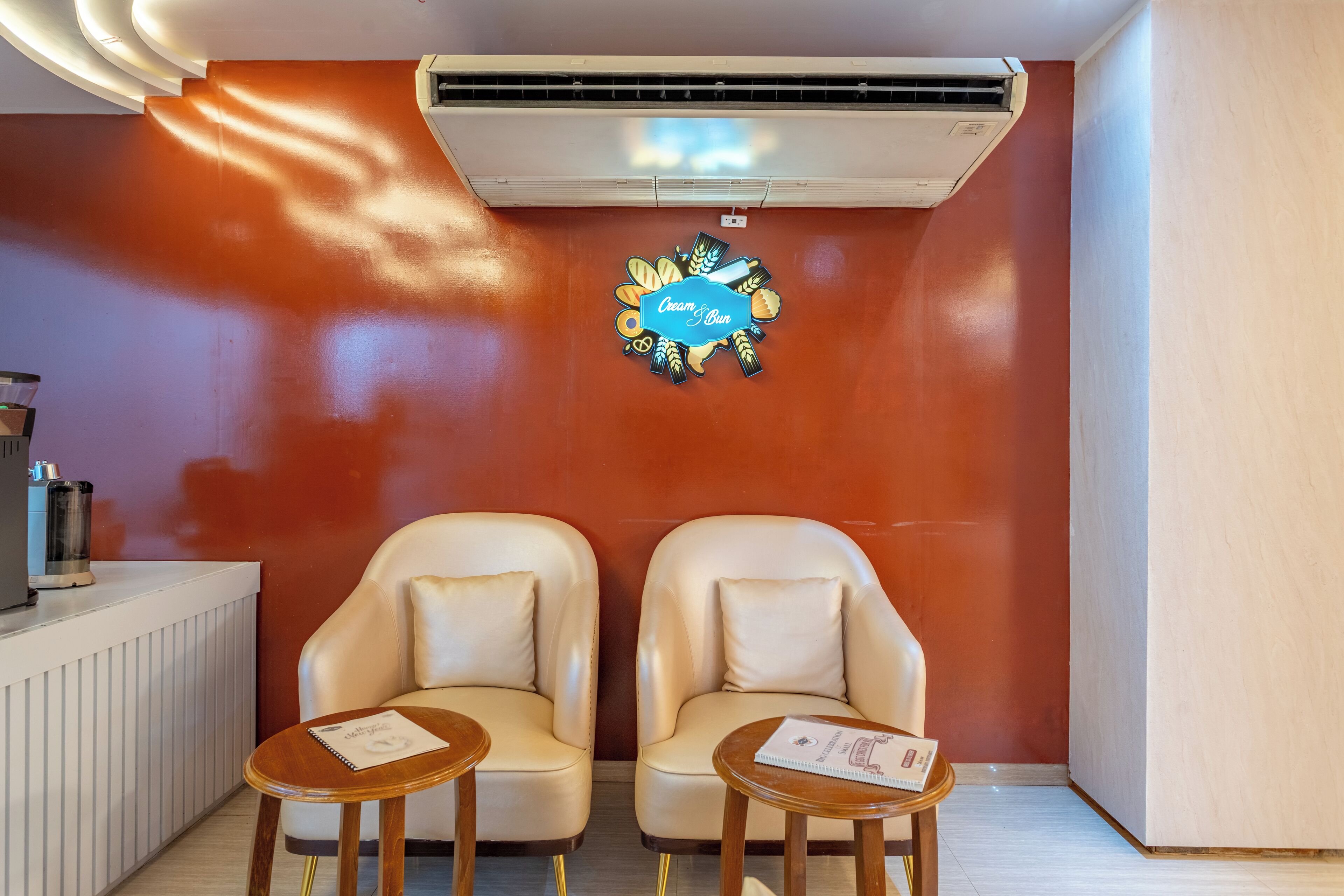 Quarto com duas poltronas de couro, uma mesinha e ar-condicionado fixado na parede.