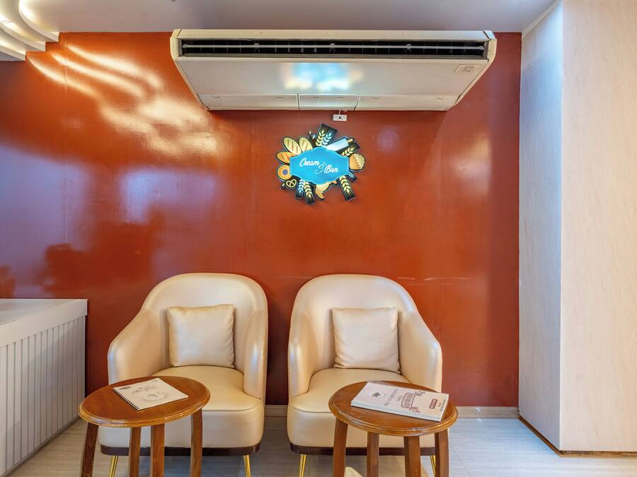 Quarto com duas poltronas de couro, uma mesinha e ar-condicionado fixado na parede.