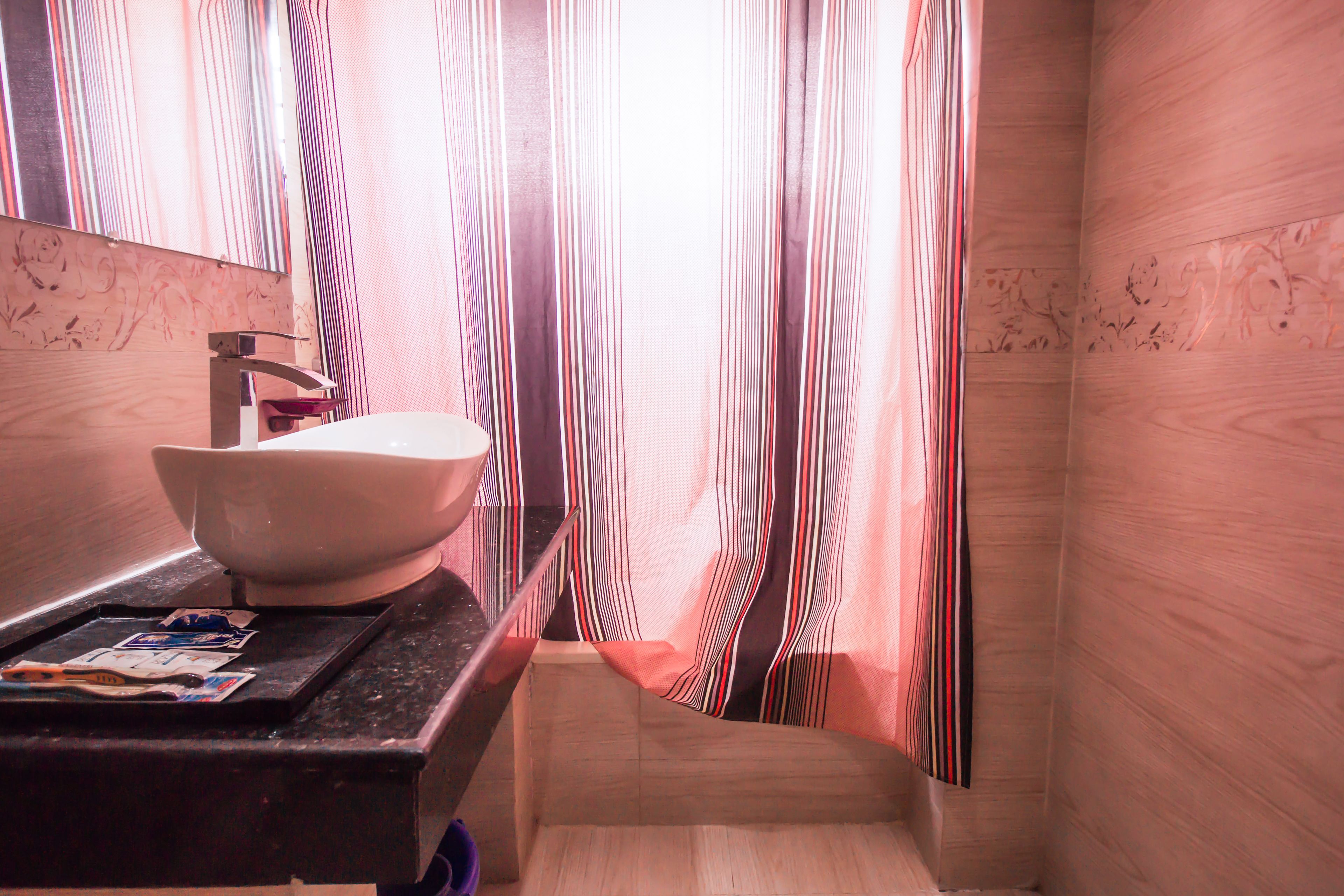 Un bagno con un mobile vanitario in legno, un lavandino bianco, tende a righe e uno specchio.