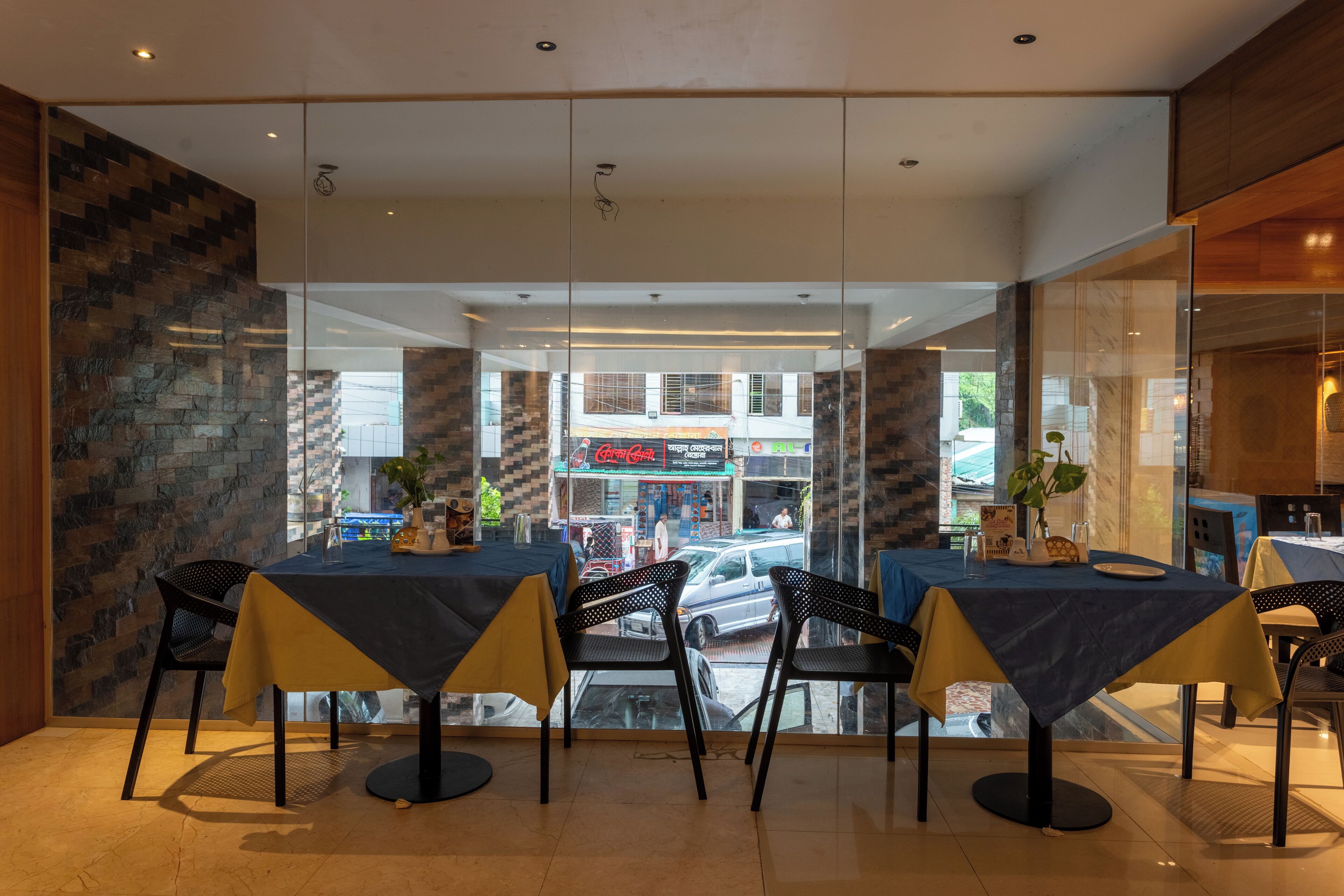 Ein moderner Essbereich mit Glaswänden, Blick auf die Straße und ein Restaurantschild im Hintergrund.