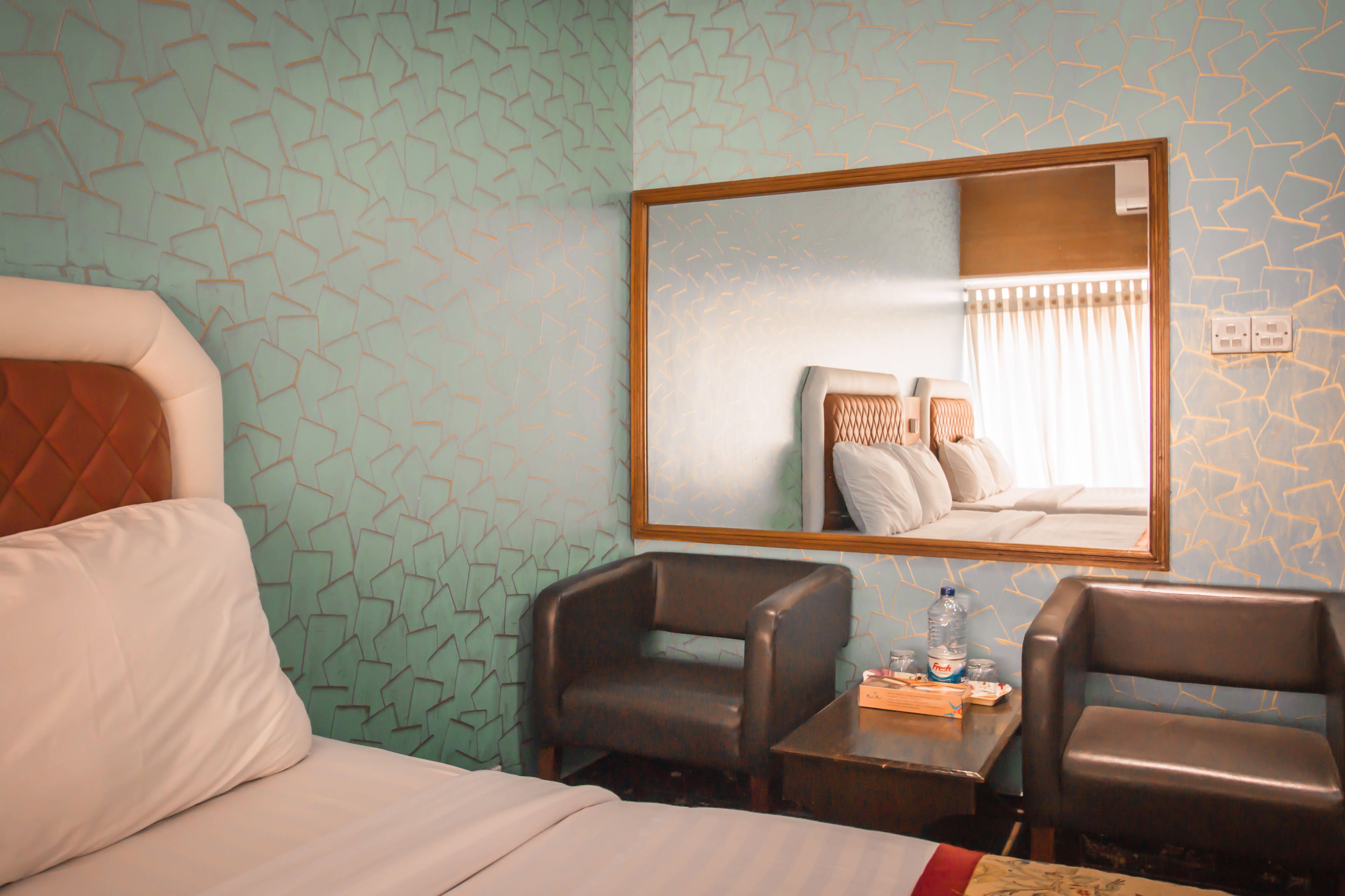 Habitación de hotel con una cama, dos sillones, una mesita y un espejo en la pared.