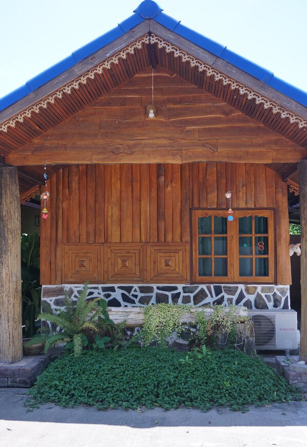 A wooden cabin with a stone foundation, a blue roof, and a window with the number 8.
