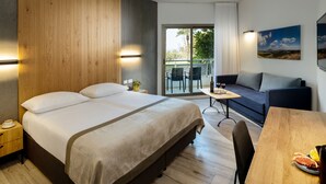 A modern hotel room with a large bed, a sofa, a dining table, and a balcony with outdoor furniture. - Kinar Galil (Ramot)