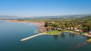 Une propriété située au bord d’un lac, dotée d’un quai, de pelouses et offrant une vue sur des collines lointaines.