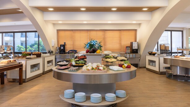 A modern breakfast buffet with various food items and a central display. - Kinar Galil (Ramot)