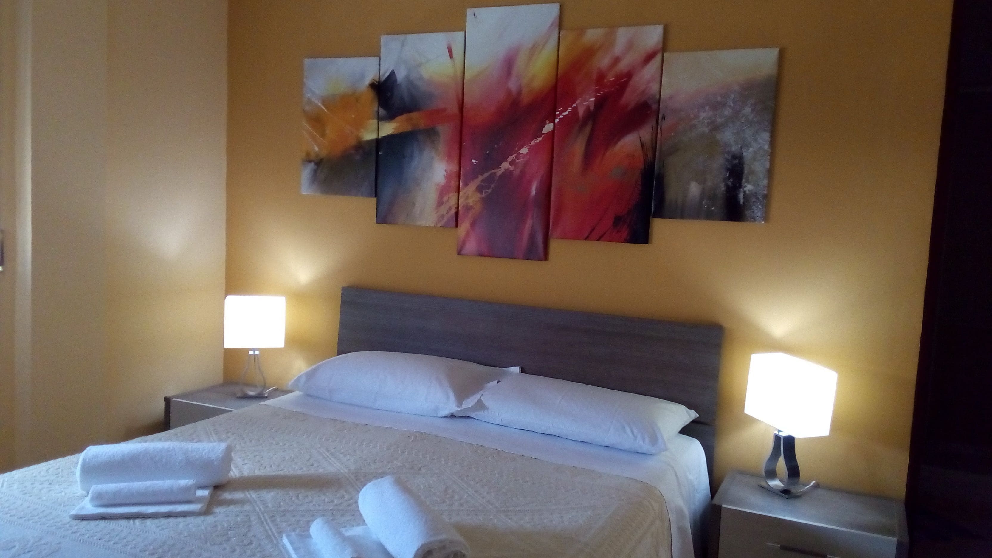 Ein Hotelzimmer mit einem Bett, zwei Nachttischen und drei an der Wand befestigten Bildern.
