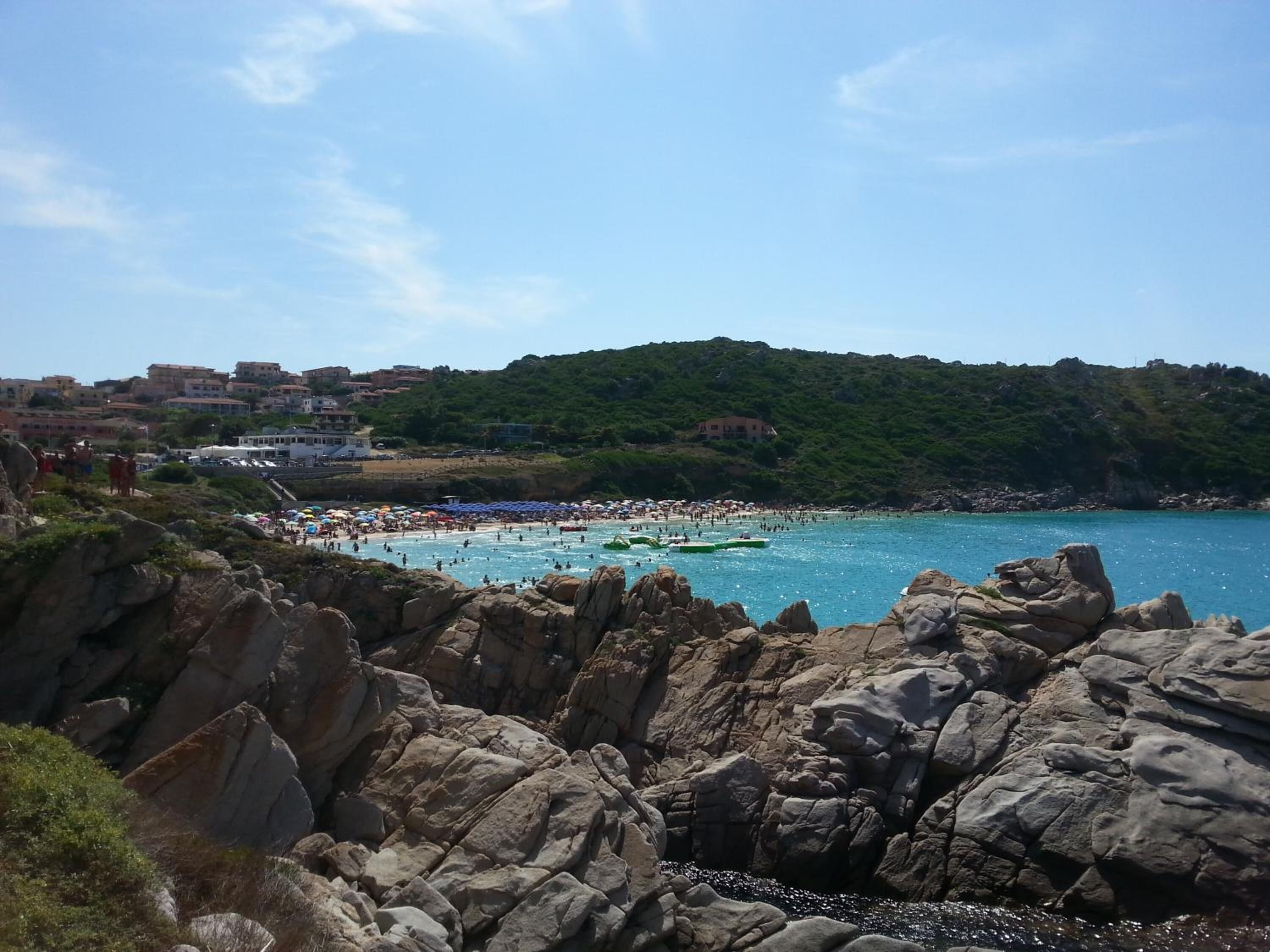 A coastal beach with rocky terrain and a view of buildings in the background.