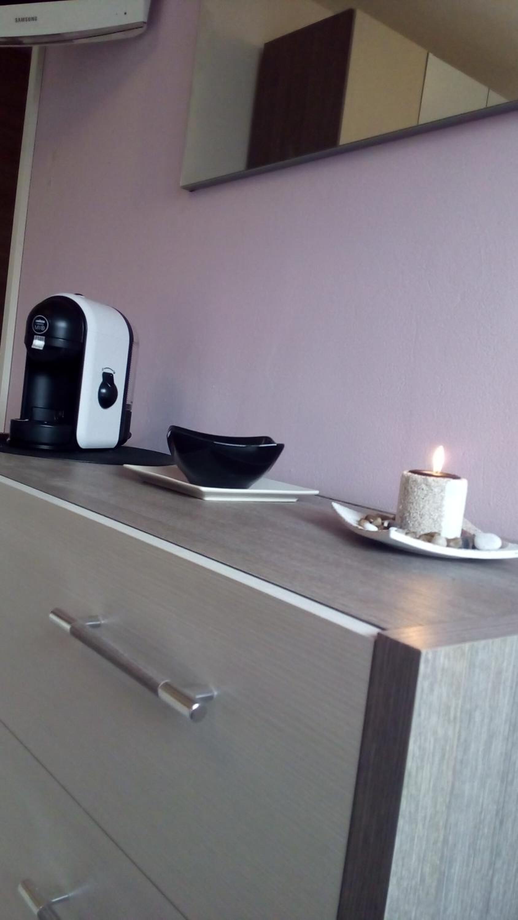 A kitchen with a coffee maker, a bowl, and a lit candle on the counter.