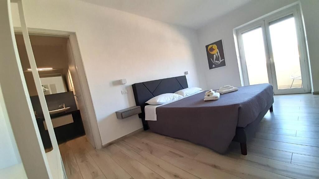 A bedroom with a bed, a wardrobe, and a door leading to another room.