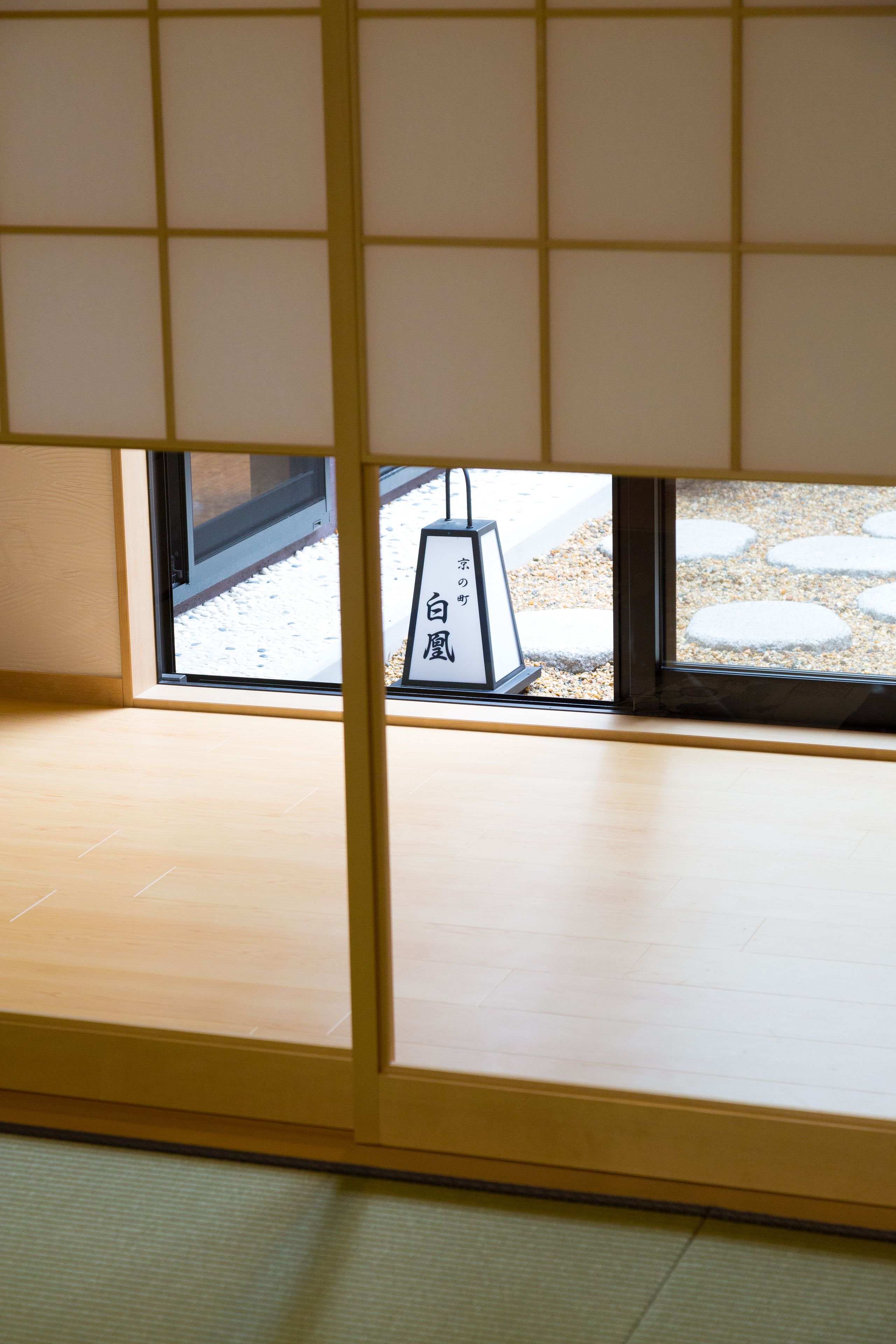 A room with tatami flooring, a sliding door, and a view of an outdoor area with stepping stones.