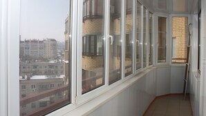 Habitación de esquina con un ventanal grande, una puerta y vistas a un paisaje urbano.