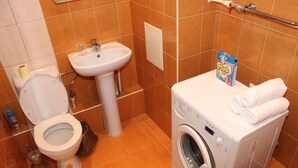 Un baño pequeño con inodoro, lavamanos y lavadora.
