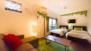 A hotel room with two beds, a sofa, a coffee table, and a TV.