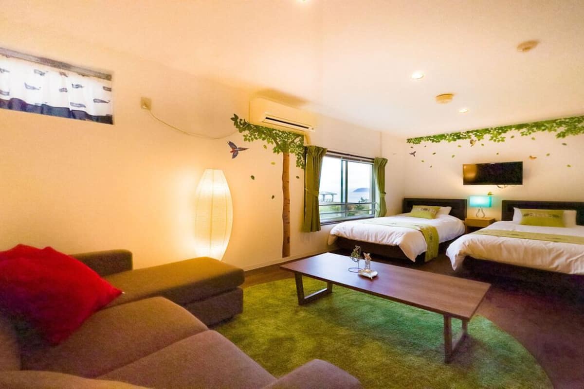A hotel room with two beds, a sofa, a coffee table, and a TV.