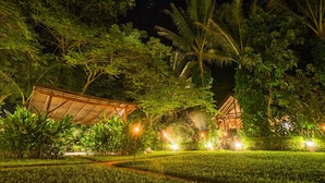 A well-lit outdoor area with a wooden structure, surrounded by lush greenery and palm trees. - Muang La Lodge (Muang La)