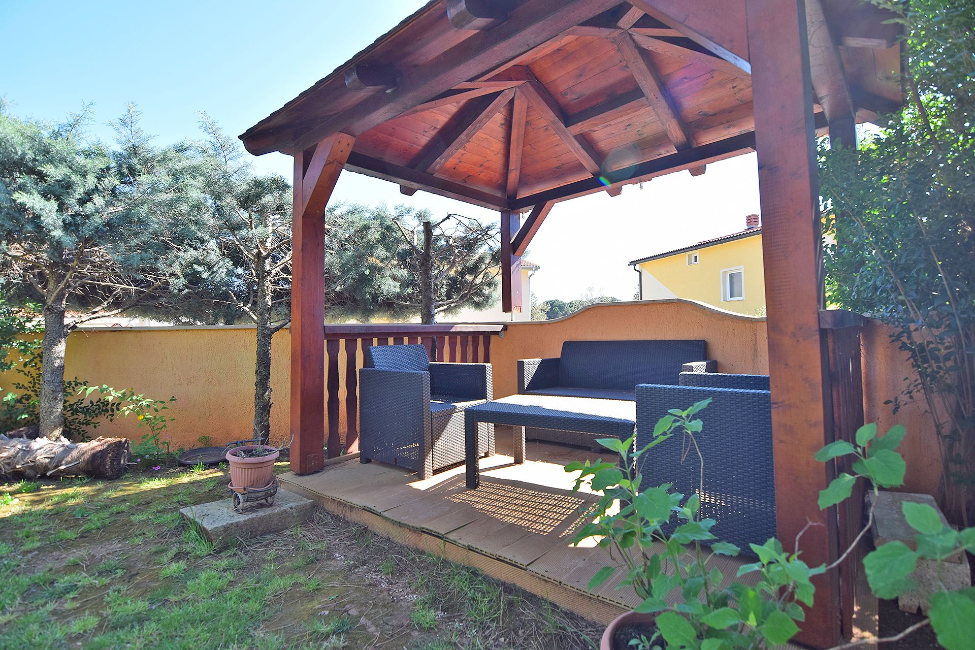 Un espace extérieur aménagé, abrité et doté de meubles en osier et d’une structure en forme de pergola.