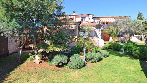 A residential property with a garden, a patio, and a building with a tiled roof. - Apartments Jeromela (Fazana)