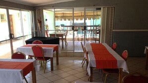 Un comedor con mesas y sillas, ventanas amplias y vistas al exterior.