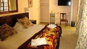 A hotel room with a bed, a TV, a chair, and a wardrobe.