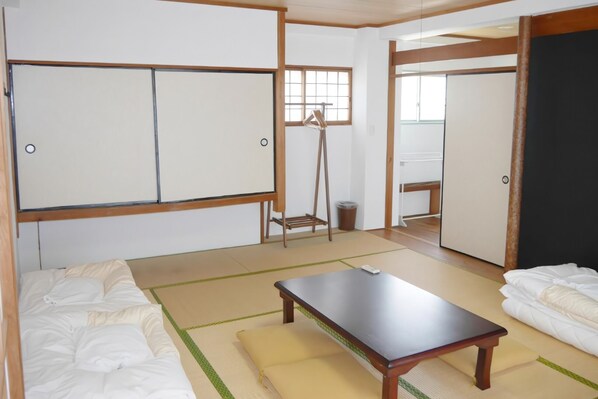 Una habitación japonesa tradicional con suelo de tatami, una mesa baja de madera y un futón.