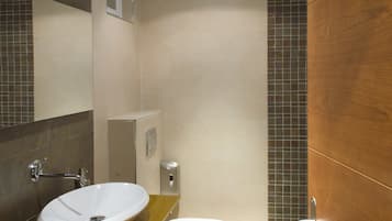 Un baño moderno con encimera amarilla, un lavabo blanco, un inodoro y una zona de ducha.