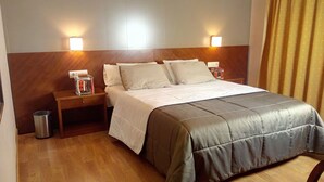 A hotel room with a bed, two bedside tables, a trash bin, and wall-mounted lamps. - Hotel Avenida (Requena)