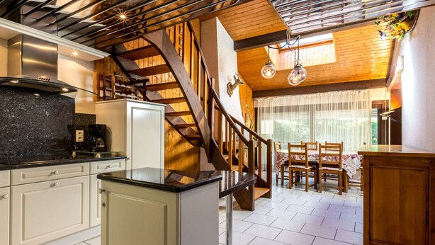 Une cuisine moderne dotée d’un îlot central, d’une cuisinière intégrée et d’un escalier menant à un niveau supérieur.