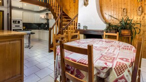 Un intérieur en bois avec une table de salle à manger ronde, un escalier et un coin cuisine.