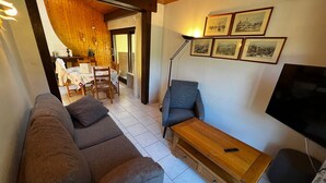 Un salon avec un canapé, une table basse en bois, un téléviseur et des tableaux encadrés accrochés au mur.