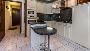Une cuisine moderne avec des meubles blancs, un îlot central doté d’un comptoir en granit et des appareils électroménagers en acier inoxydable.