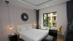 Een moderne hotelkamer met een groot bed, een zwarte leren bank, een kleine tafel en een stoel. Er is een raam met uitzicht.
