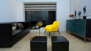 Een moderne woonkamer met een zwarte bank, een gele fauteuil en een blauwgroene kast.