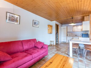 Une cuisine moderne avec des meubles blancs, un micro-ondes bleu et une table à manger en bois, assortie de chaises en métal.
