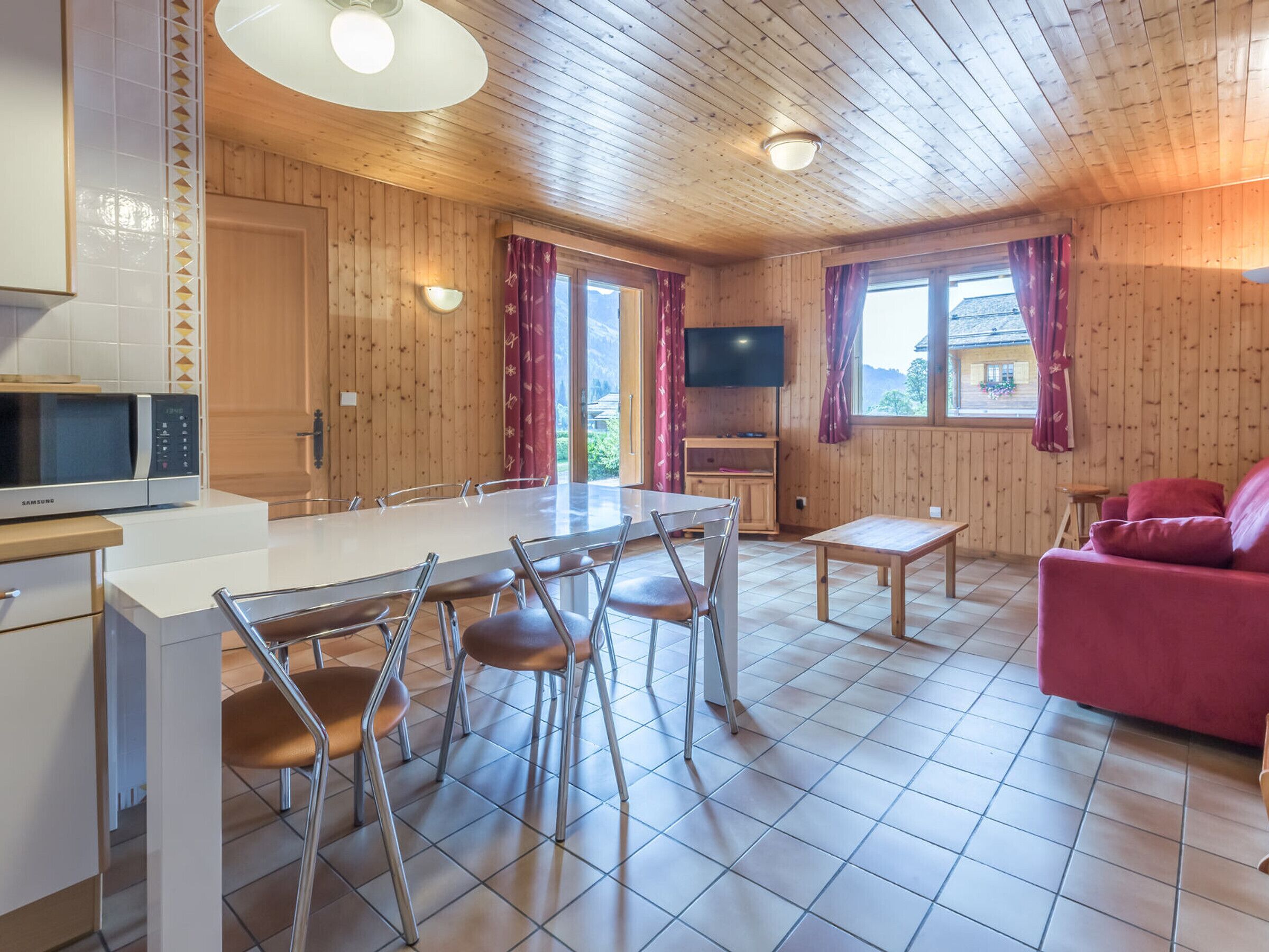 Una cucina moderna con zona pranzo, televisione a schermo piatto e divano rosso.