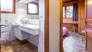 Une salle de bain moderne avec un meuble-lavabo blanc, un grand miroir et une fenêtre.