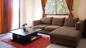 Ein Wohnzimmer mit einem braunen Sofa, einem dunklen Couchtisch und einem roten Teppich.
