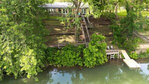 Eine rustikale Holzhütte mit einer Holzterrasse, einer Treppe zu einer Veranda und einem Steg, der sich in ruhiges Wasser erstreckt.