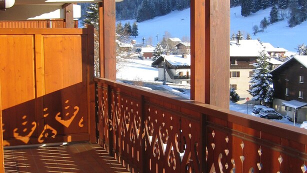A balcony with a wooden railing and a view of a snowy village. - Lovely apartment near ski slopes and village, pets allowed (La Clusaz)