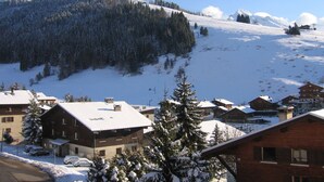 A snow-covered mountain village with traditional wooden buildings, a ski slope, and a clear blue sky. - Lovely apartment near ski slopes and village, pets allowed (La Clusaz)